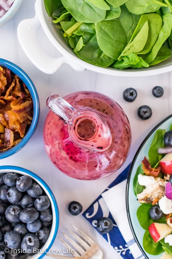 An overhead picture of a jar of Blueberry Balsamic Salad Dressing and bowls of salad ingredients