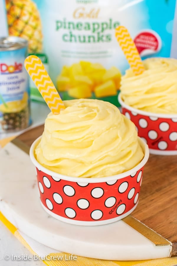 Two red and white polkadot cups filled with a pineapple Dole Whip swirl and wooden spoons