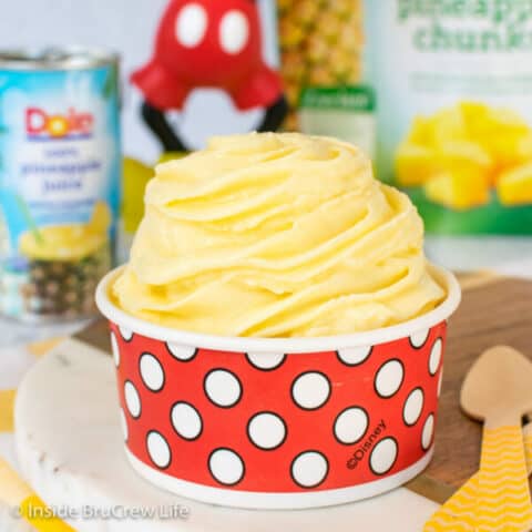 A red and white polkadot cup filled with a pineapple dole whip swirl in it