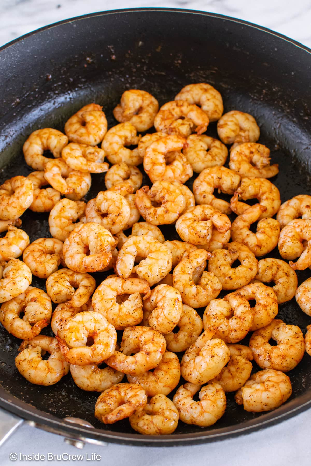 A skillet filled with pan fried shrimp.