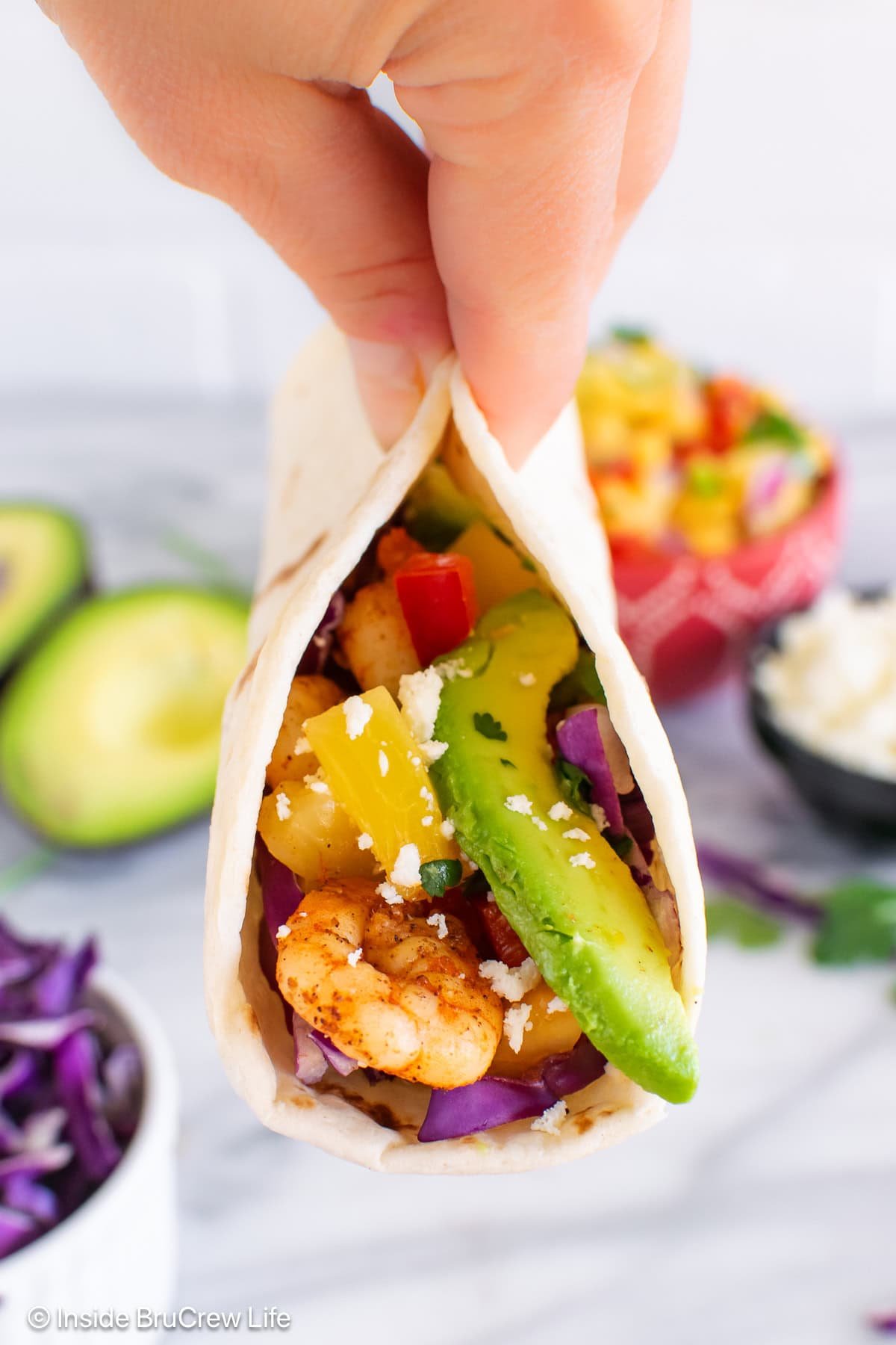 A shrimp taco being lifted off a plate.