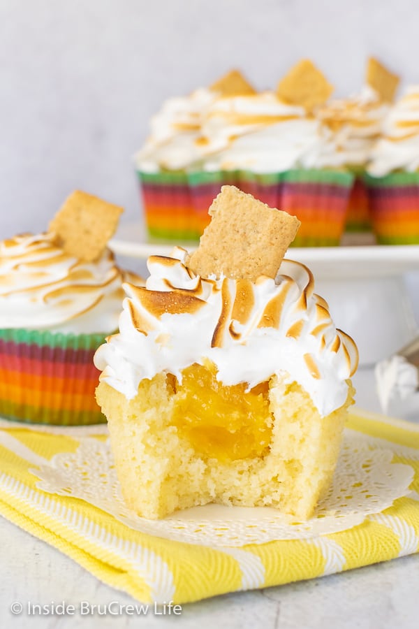 A close up picture of the center of a lemon meringue cupcake sitting on a white doily on a yellow towel