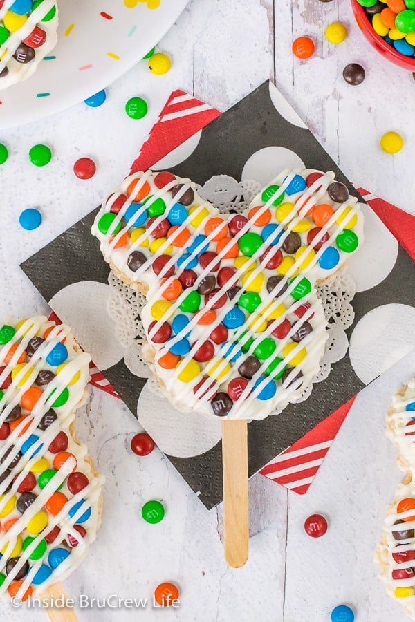 A close up overhead picture of a M&M's Mickey Mouse Rice Krispie Treat on a stick