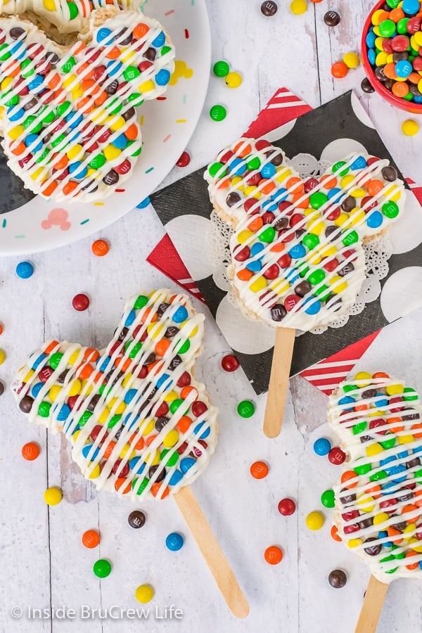 Overhead picture of M&M's Mickey Mouse Rice Krispie Treats on a white background with M&M's scattered around them