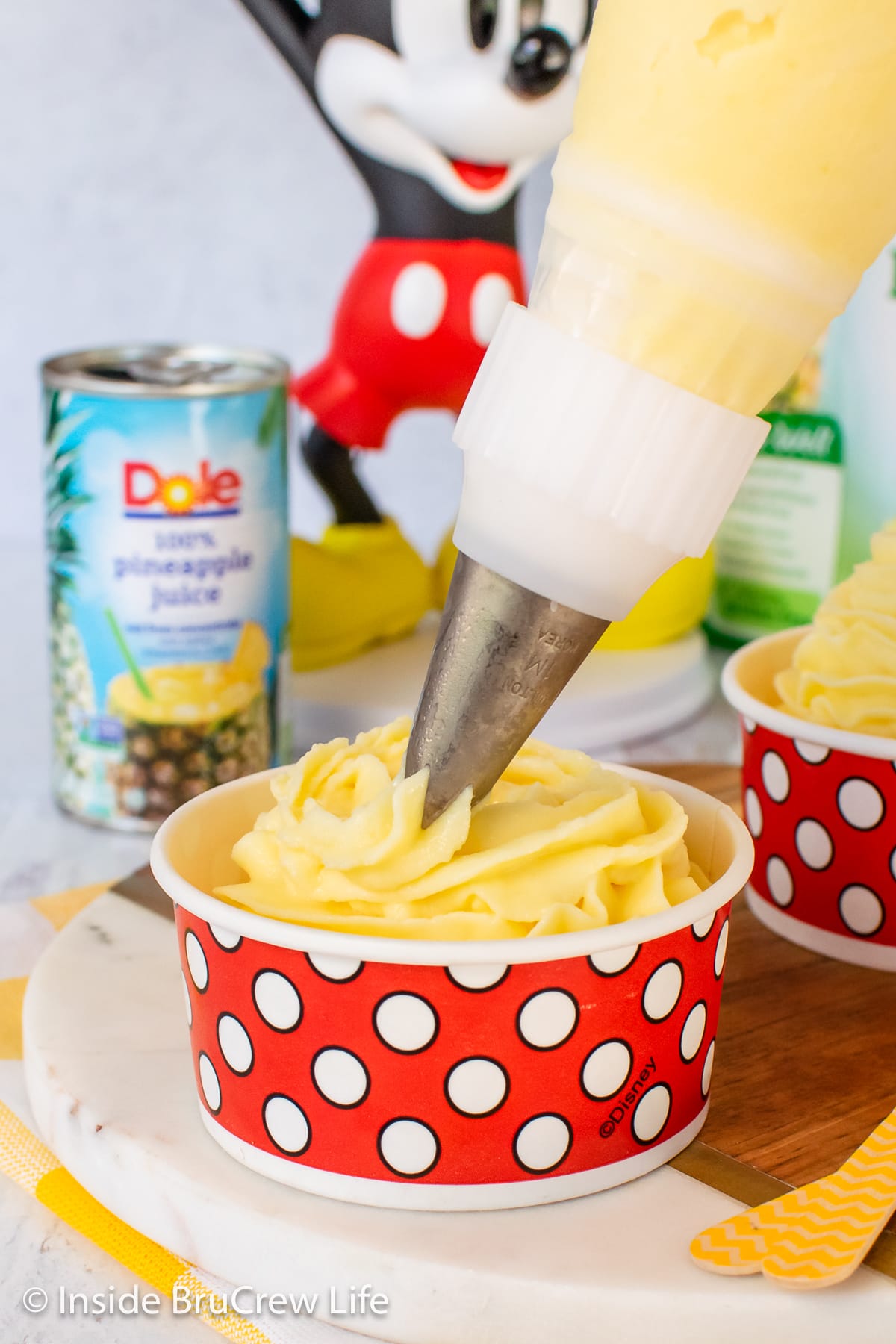 Frozen pineapple whip being piped into a serving cup.