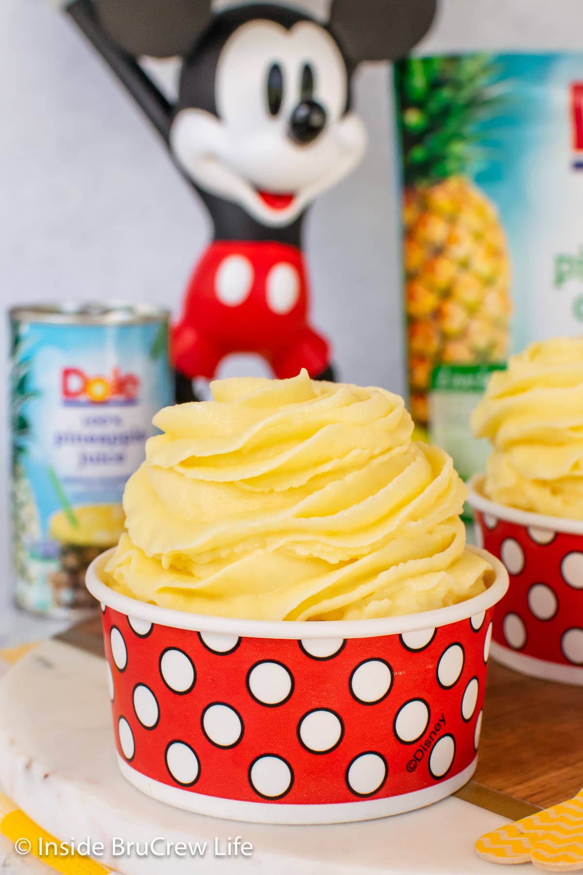 A swirl of pineapple whip in a red and white polkadot cup.