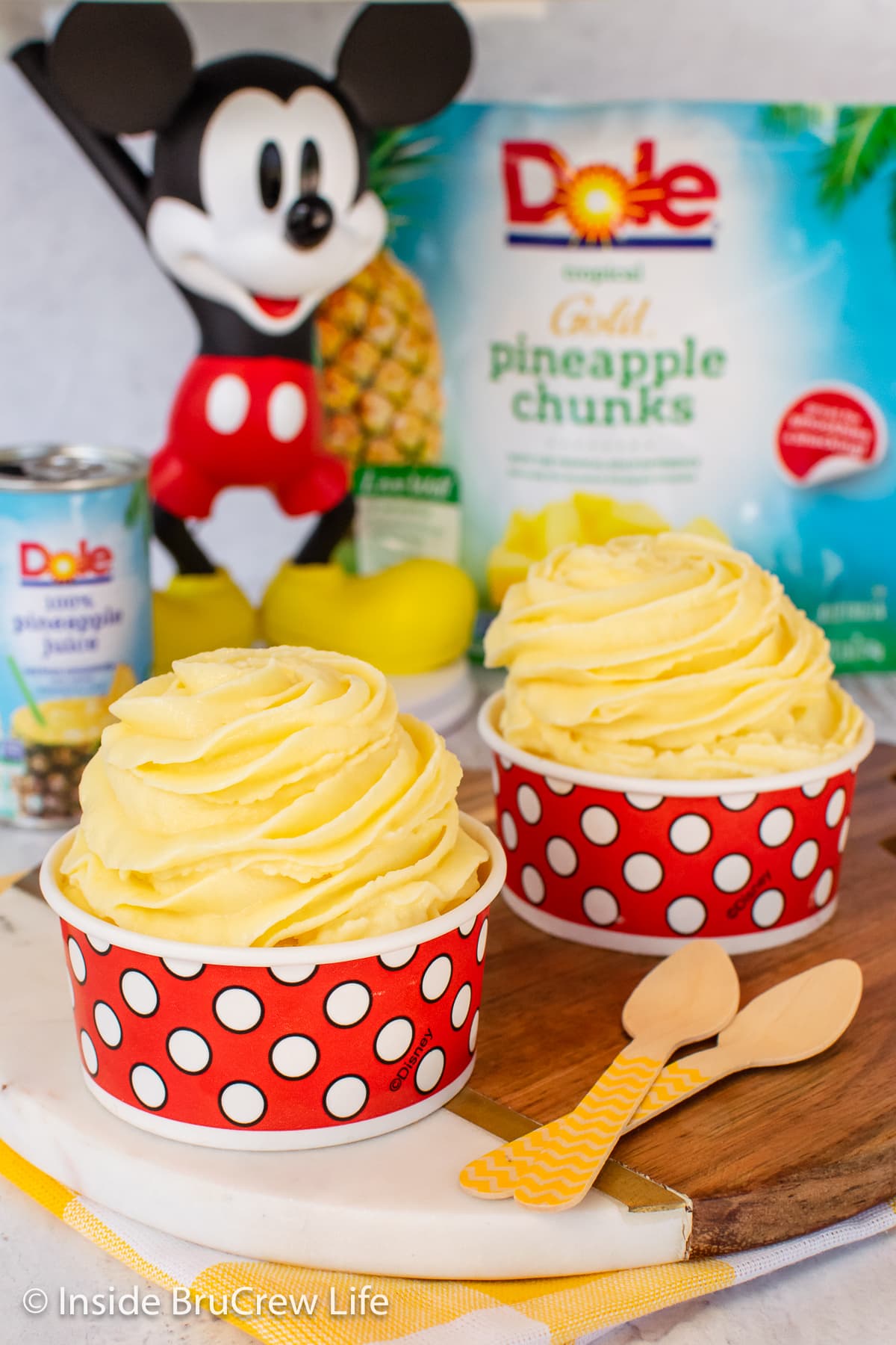 Two paper cups filled with a swirl of pineapple sorbet.