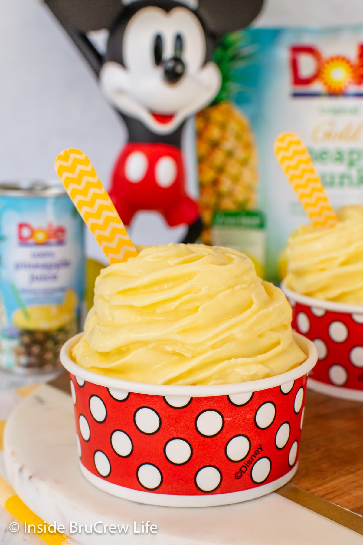 A red and white cup filled with a swirl of pineapple flavored ice cream.