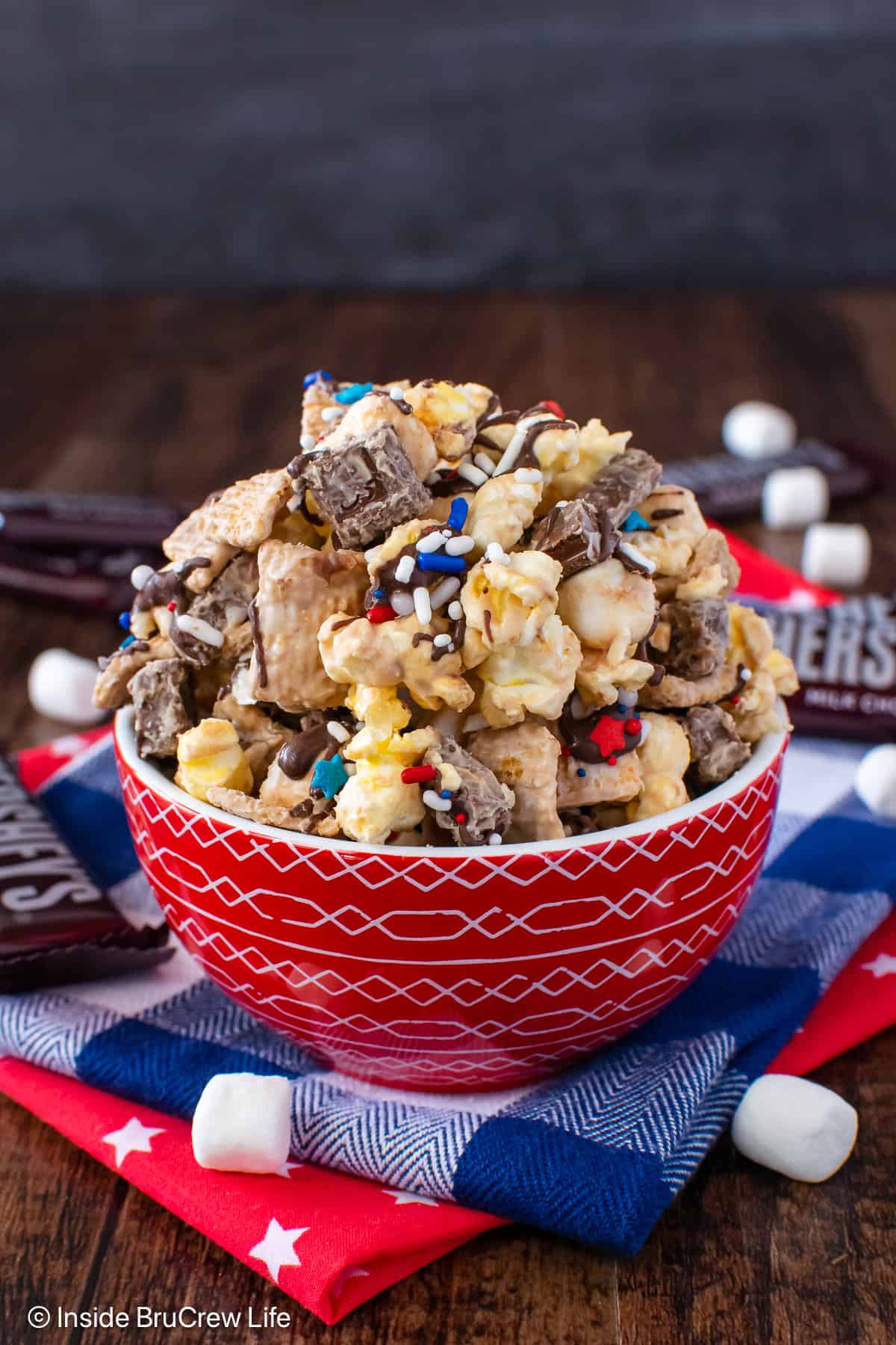 A red bowl filled with a s'mores popcorn snack mix.