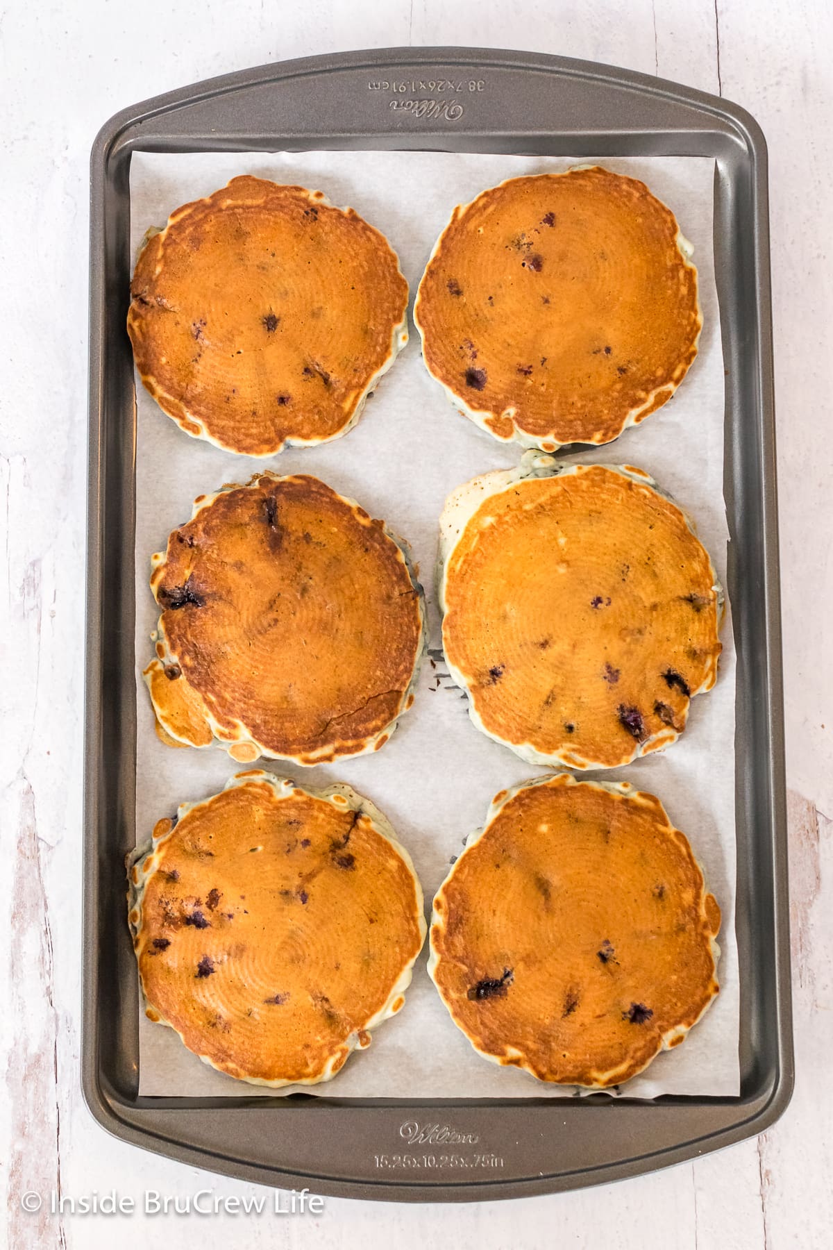 Six pancakes on a sheet pan.