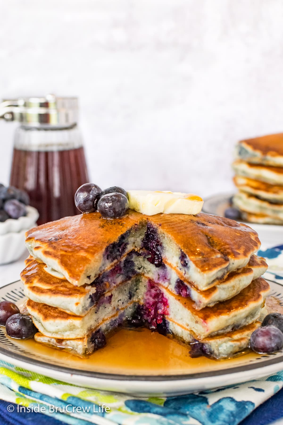 A stack of pancakes on a plate cut showing the blueberries inside.