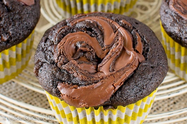 A close up pictures of the top of a chocolate banana muffin with Nutella swirls on it