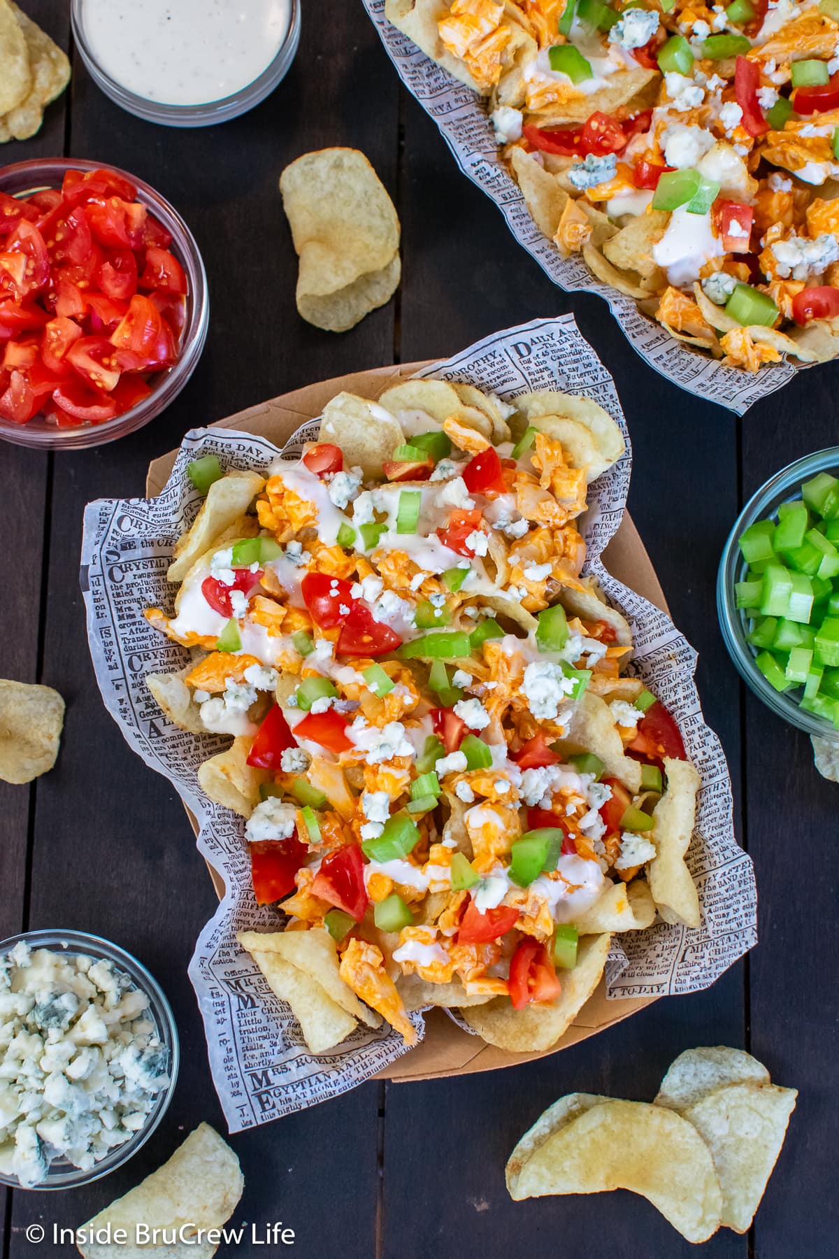 A bowl of chips topped with spicy chicken and veggies.