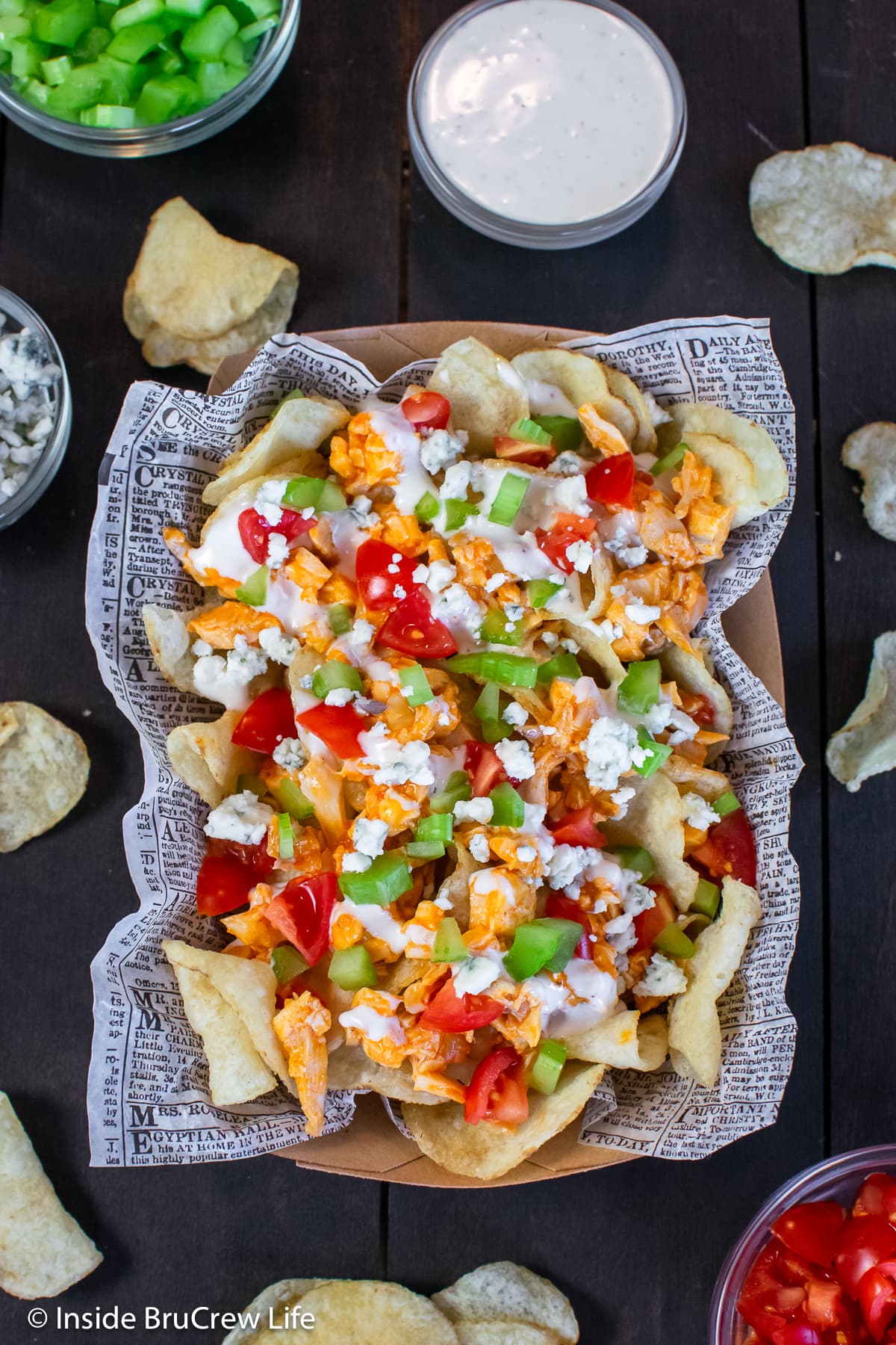 A bowl of chips topped with dressing, chicken, and veggies.