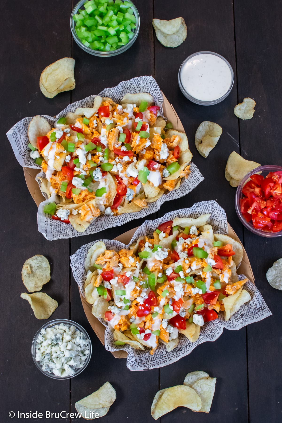 Two bowls filled with chips and spicy chicken toppings.