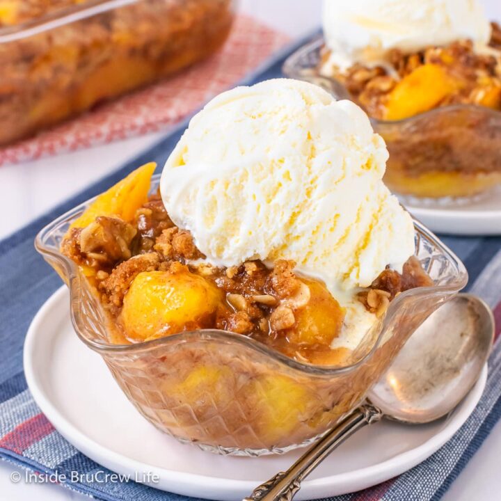 A bowl of crunchy oatmeal topping, peaches, and ice cream.