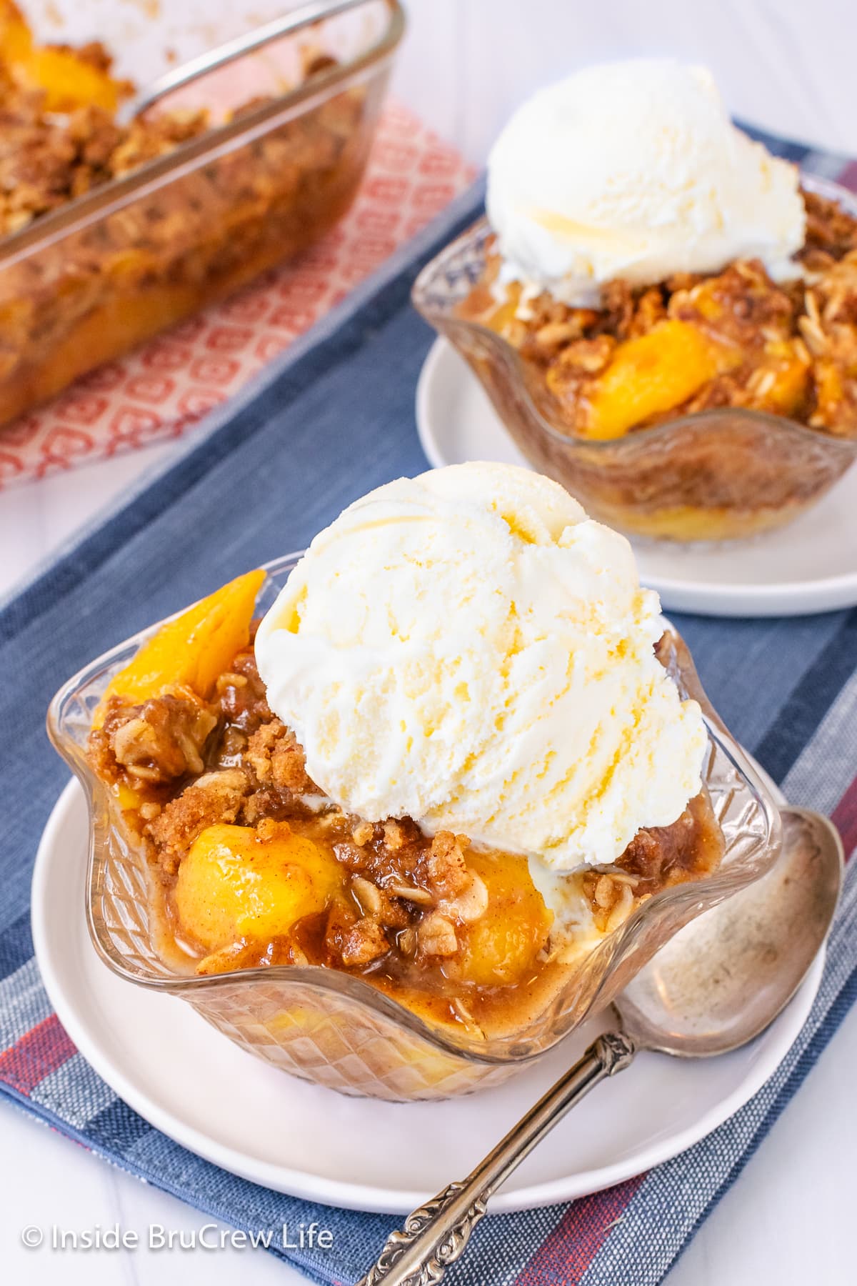 Two bowls with peach crisp and vanilla ice cream.