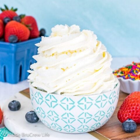 A blue and white bowl with a swirl of whipped cream in it and berries behind it