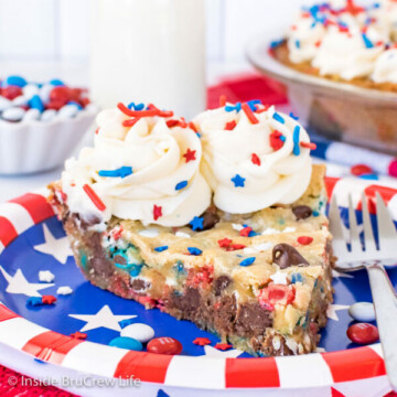 A red, white, and blue plate with a slice of chocolate chip cookie pie decorated with frosting swirls and sprinkles