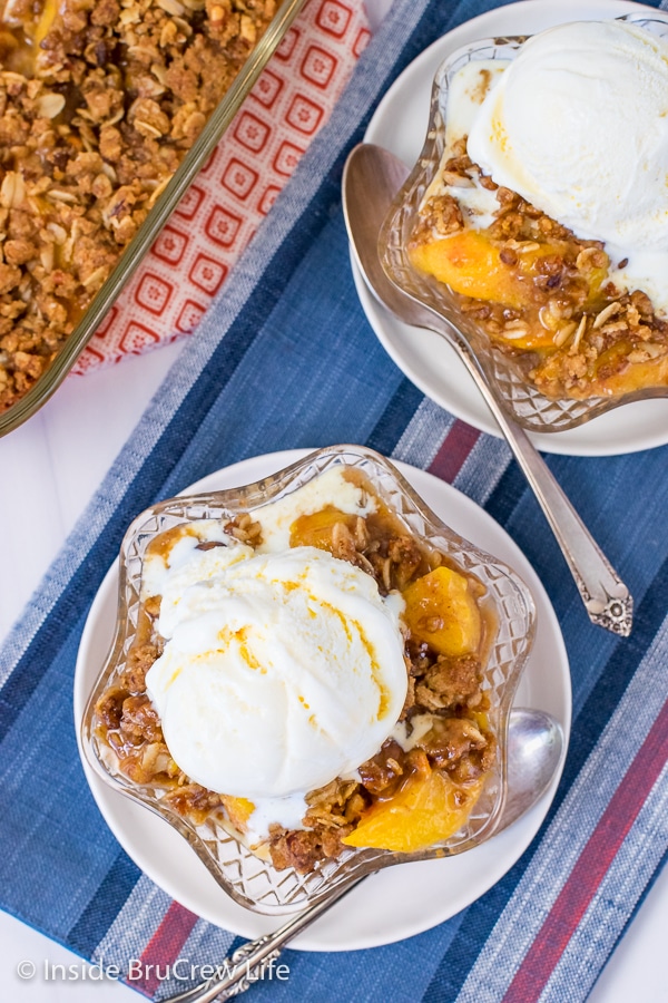 Overhead picture of two bowls on a blue towel filled with peach crisp and topped with vanilla ice cream