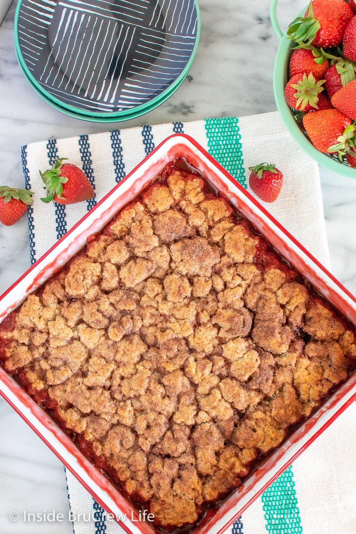 A white pan filled with strawberry pie filling and cinnamon sugar biscuits.