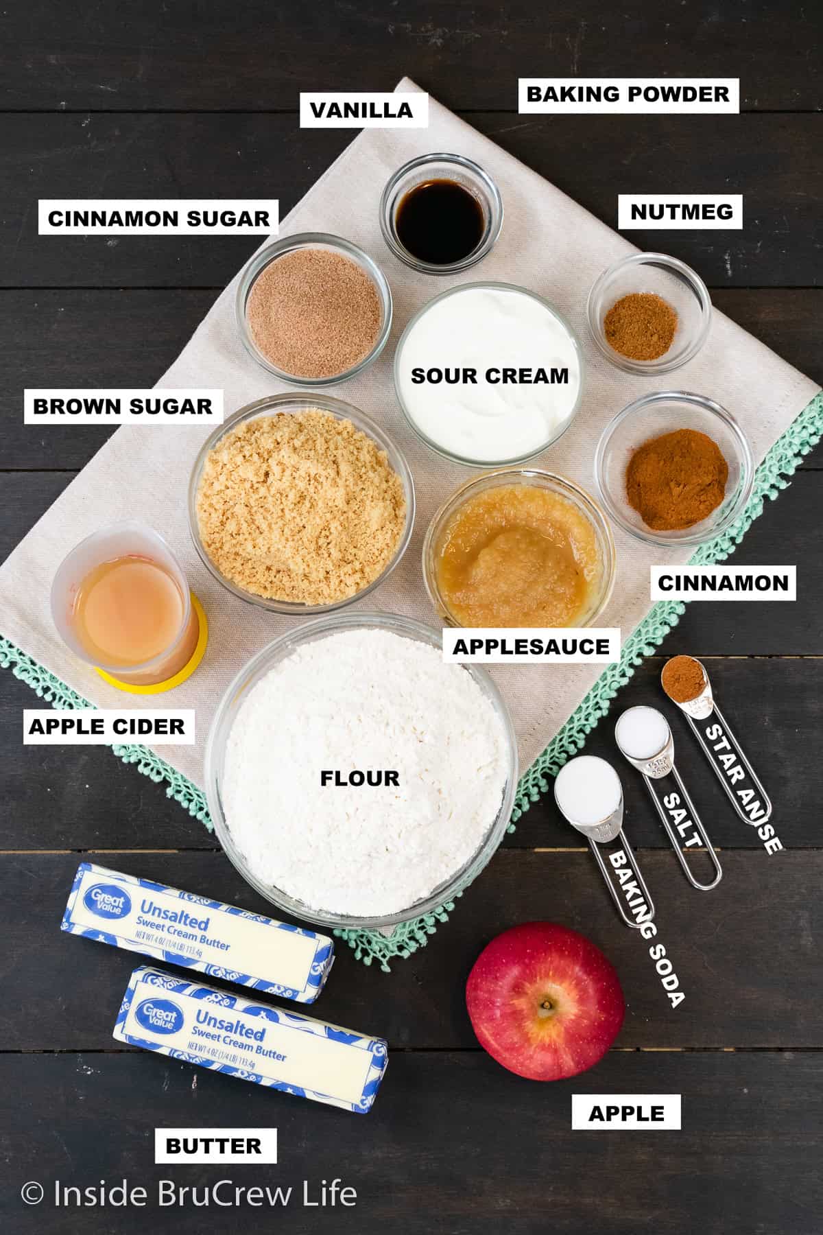 Apple Cider Donut Holes - these sweet little baked donut holes are made with apples, applesauce, and apple cider. The cinnamon sugar coating adds a great crunch to each one. Ingredients for apple cider donut holes on a dark brown board with text labels.