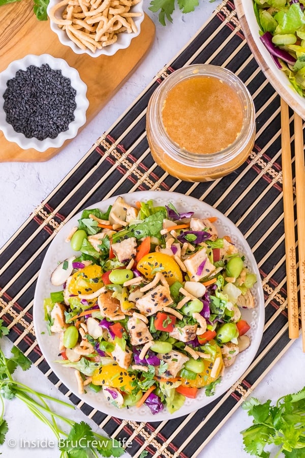 Overhead picture of an asian chicken salad on a white plate and black placemat