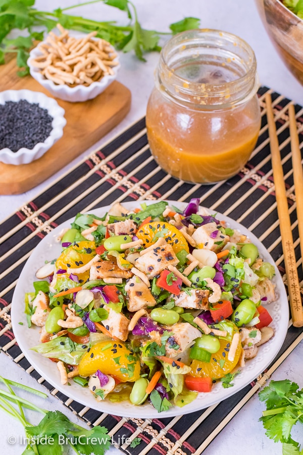 A white plate on a black placemat filled with an Asian Chicken Salad.