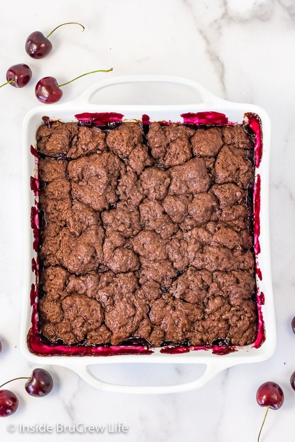 An overhead picture of a white pan filled with baked chocolate cherry cobbler