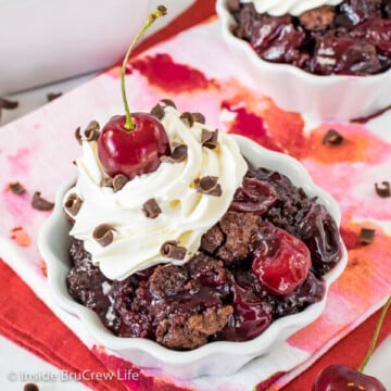 A white bowl filled with chocolate cherry cobbler and homemade whipped cream