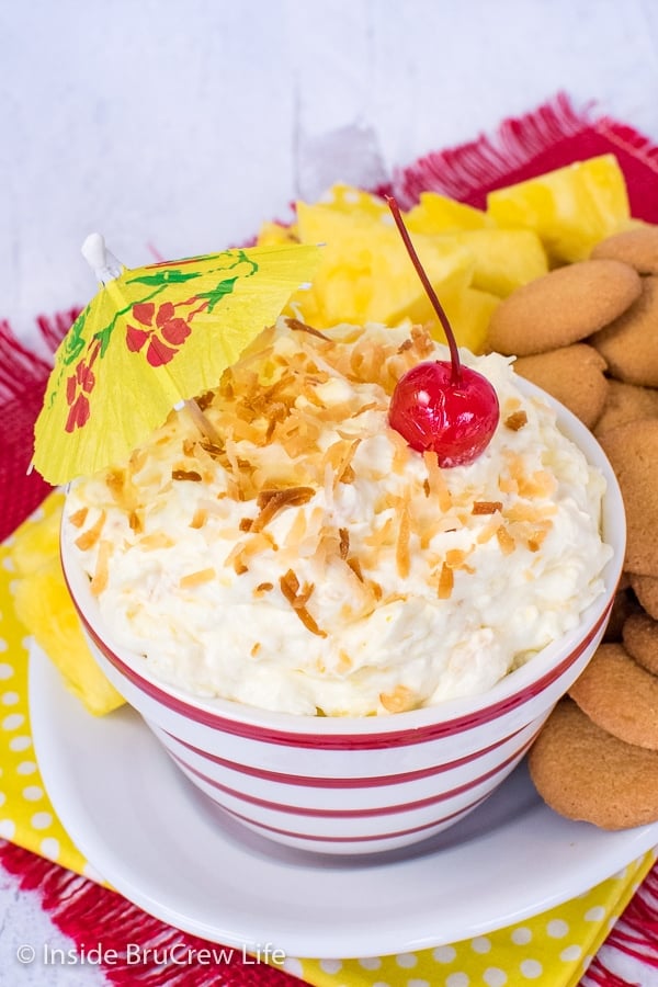 Close up picture of the top of a bowl filled with pina colada fruit dip and topped with toasted coconut and a cherry