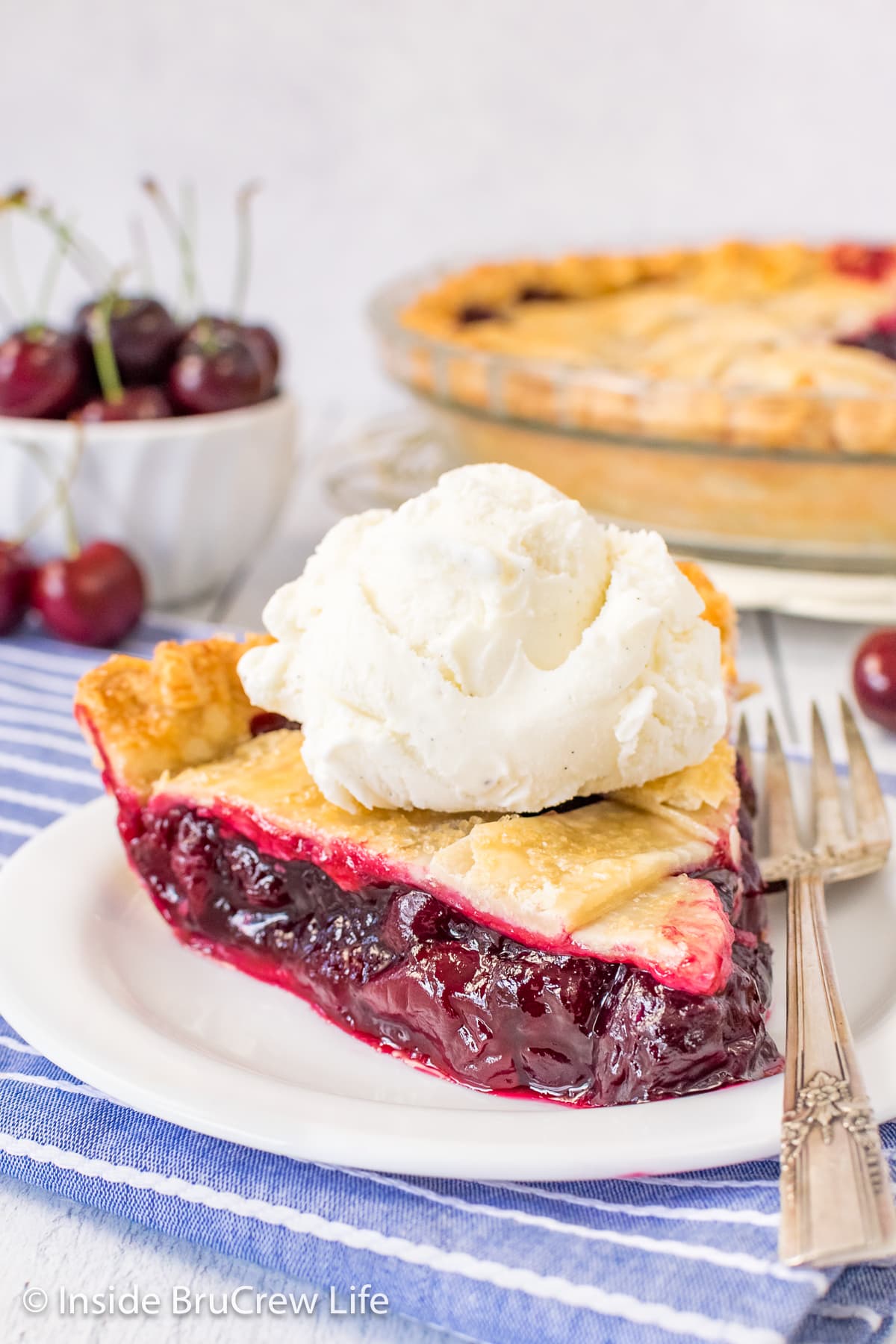 A slice of pie with vanilla ice cream on a white plate.