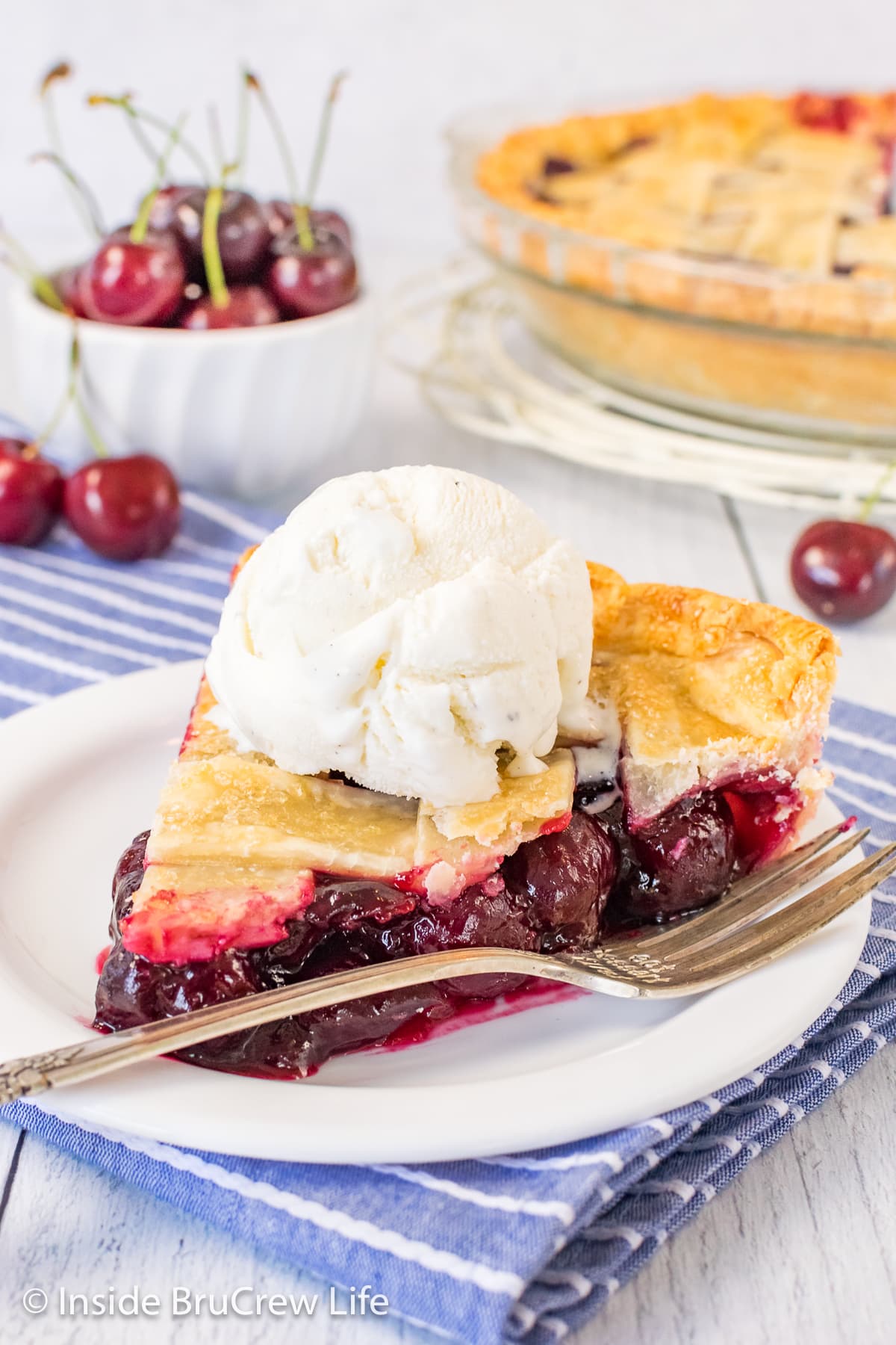 A white plate with a slice of pie topped with ice cream.