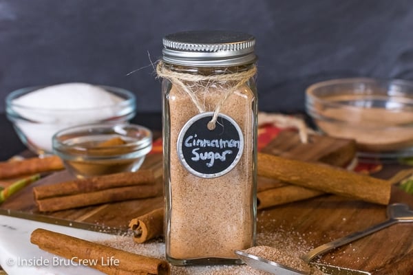 A wood tray with cinnamon sticks and a clear jar filled with homemade cinnamon sugar.