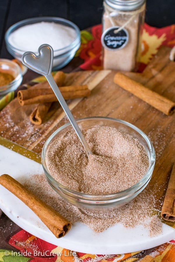 A clear bowl on a wood tray filled with homemade cinnamon sugar.