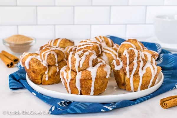 A white background with a white plate filled with monkey bread muffins