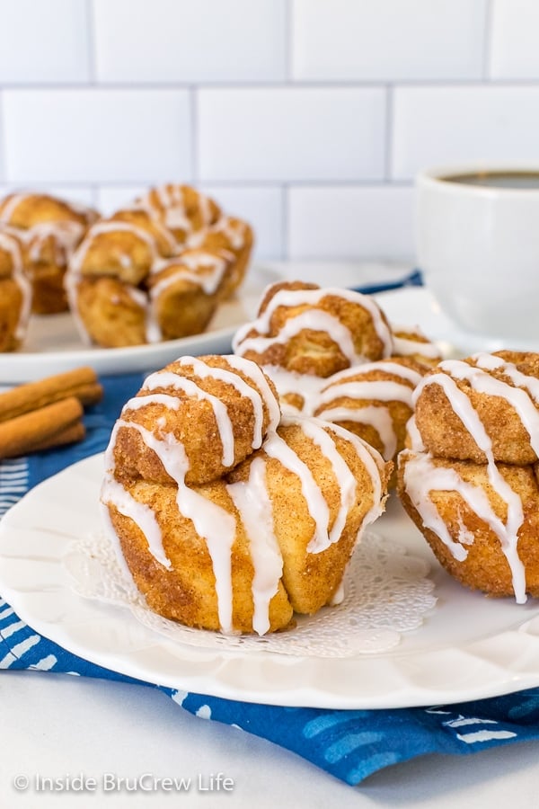 A white plate with three monkey bread muffins drizzled with glaze on it