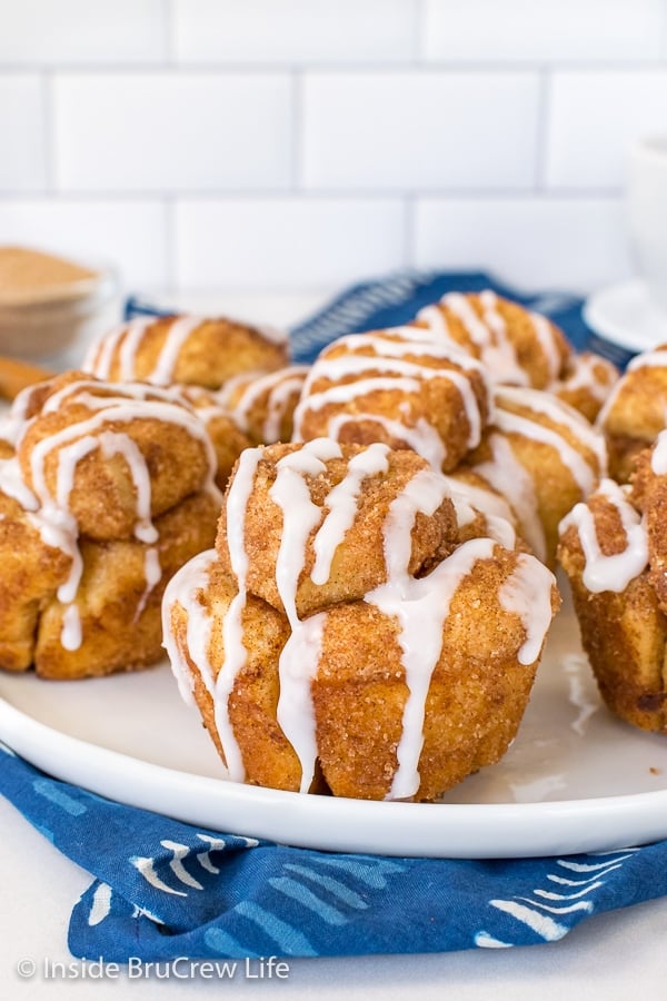 A white plate with monkey bread muffins drizzled with sweet glaze on it