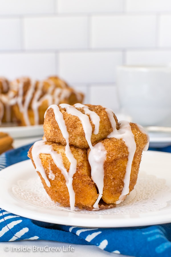 A white plate with a monkey bread muffin drizzled with glaze on it