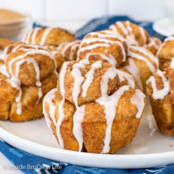 A white plate with monkey bread muffins drizzled with glaze on it