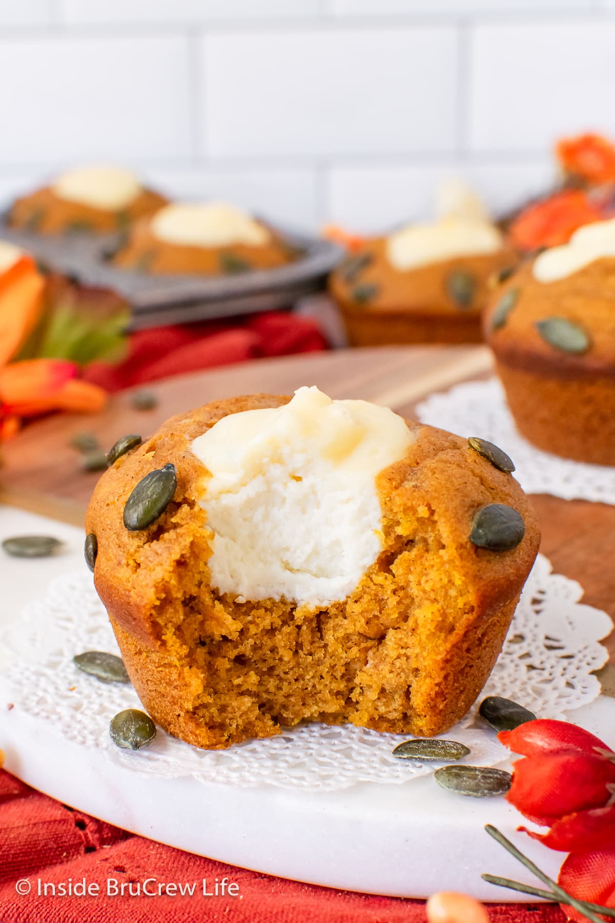 A pumpkin muffin with a bite out of it showing the cheesecake filling.