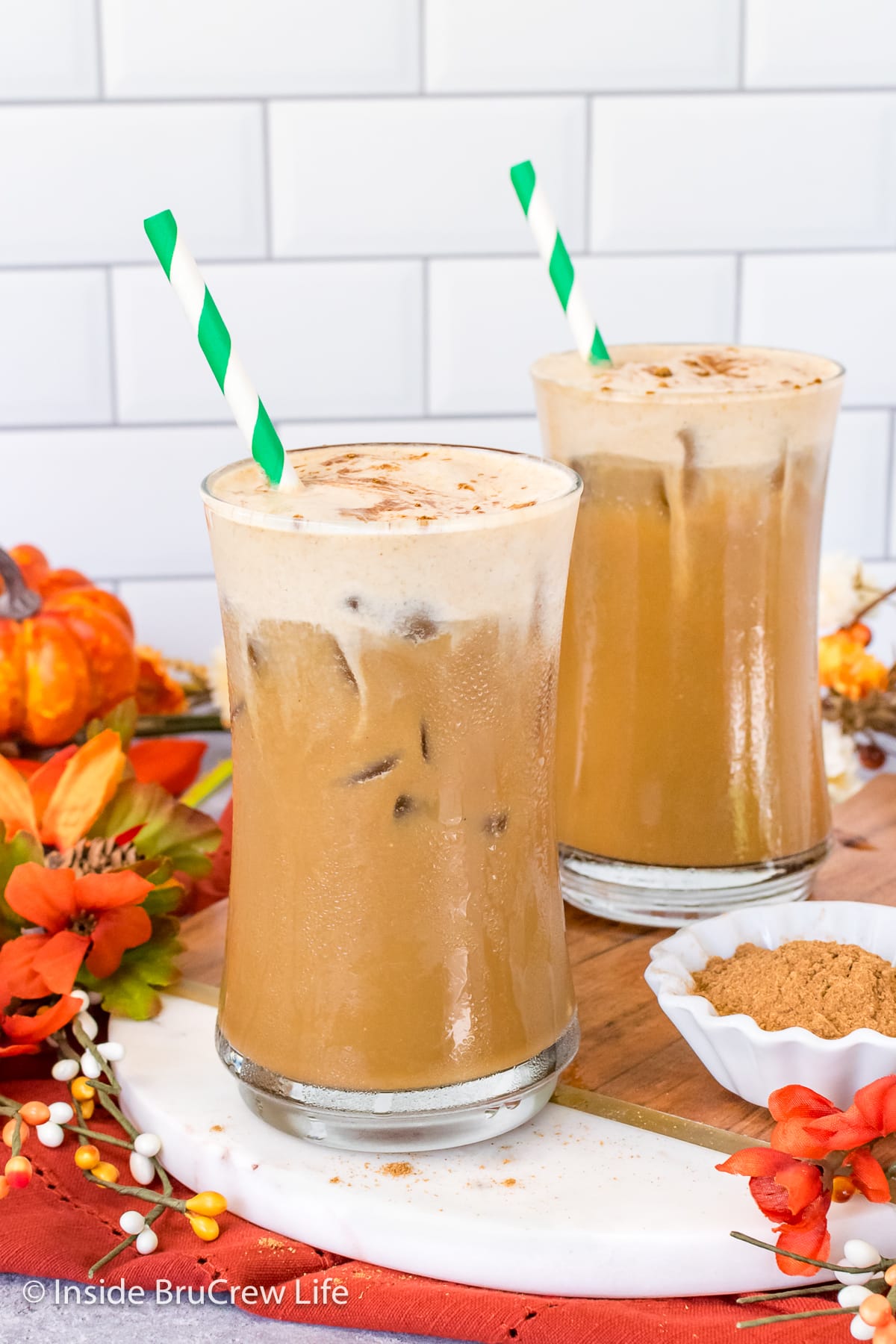 Two clear glasses filled with iced coffee and cold foam.