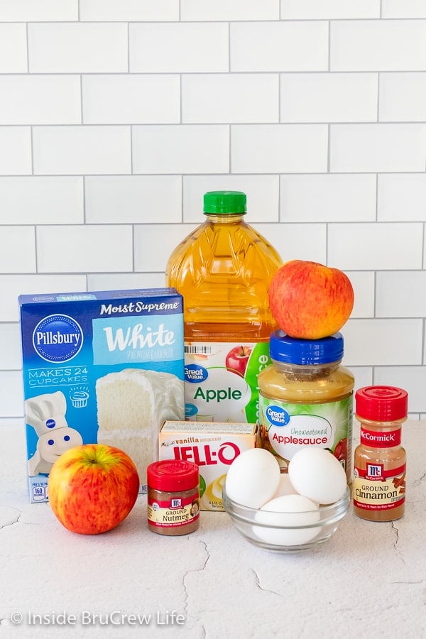 Ingredients needed to make a cinnamon apple cake on a white board.