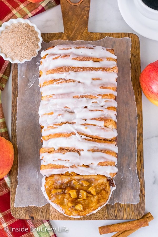 Overhead picture of a wood tray with a loaf of apple cinnamon pull apart bread drizzled with glaze