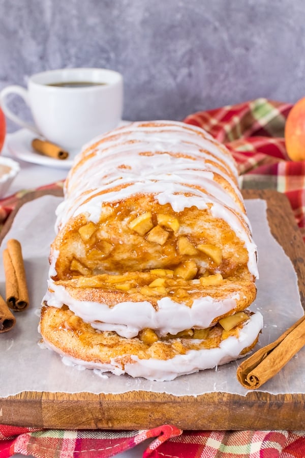 A loaf of apple cinnamon pull apart bread with two slices of the bread lying down showing the apple filling