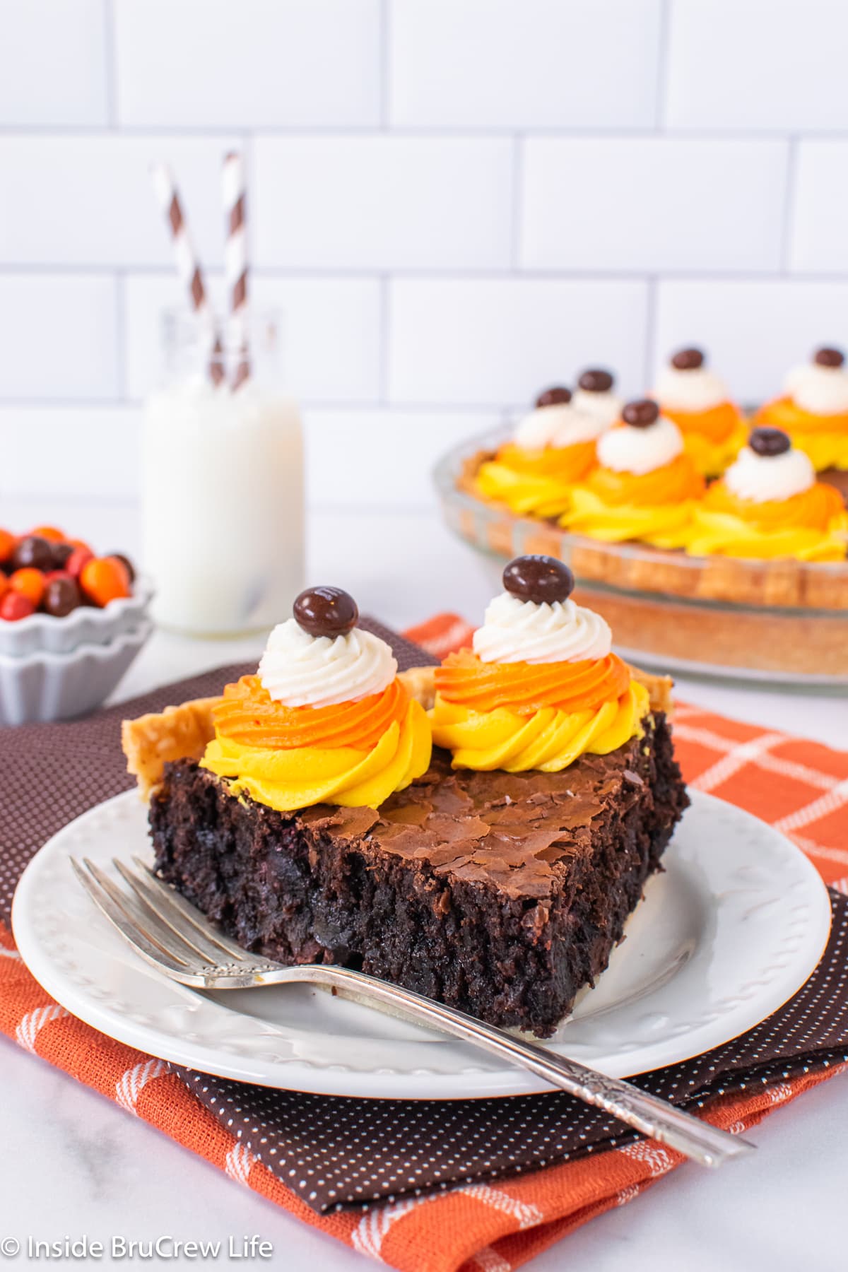 A slice of brownie pie with Halloween frosting swirls on a white plate.