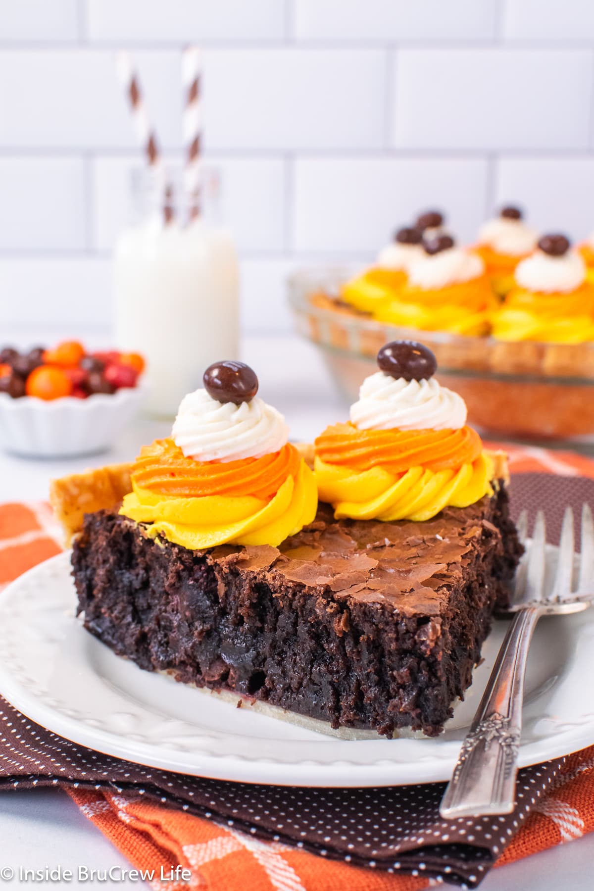 A slice of brownie pie with Halloween frosting swirls on a white plate.