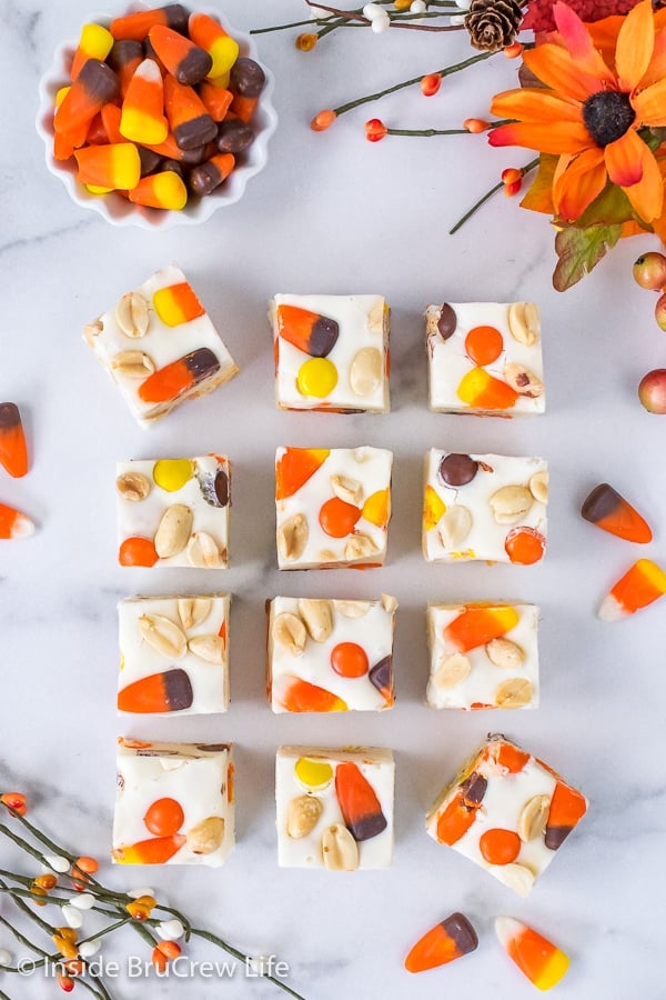 Overhead picture of squares of candy corn fudge on a white marble background