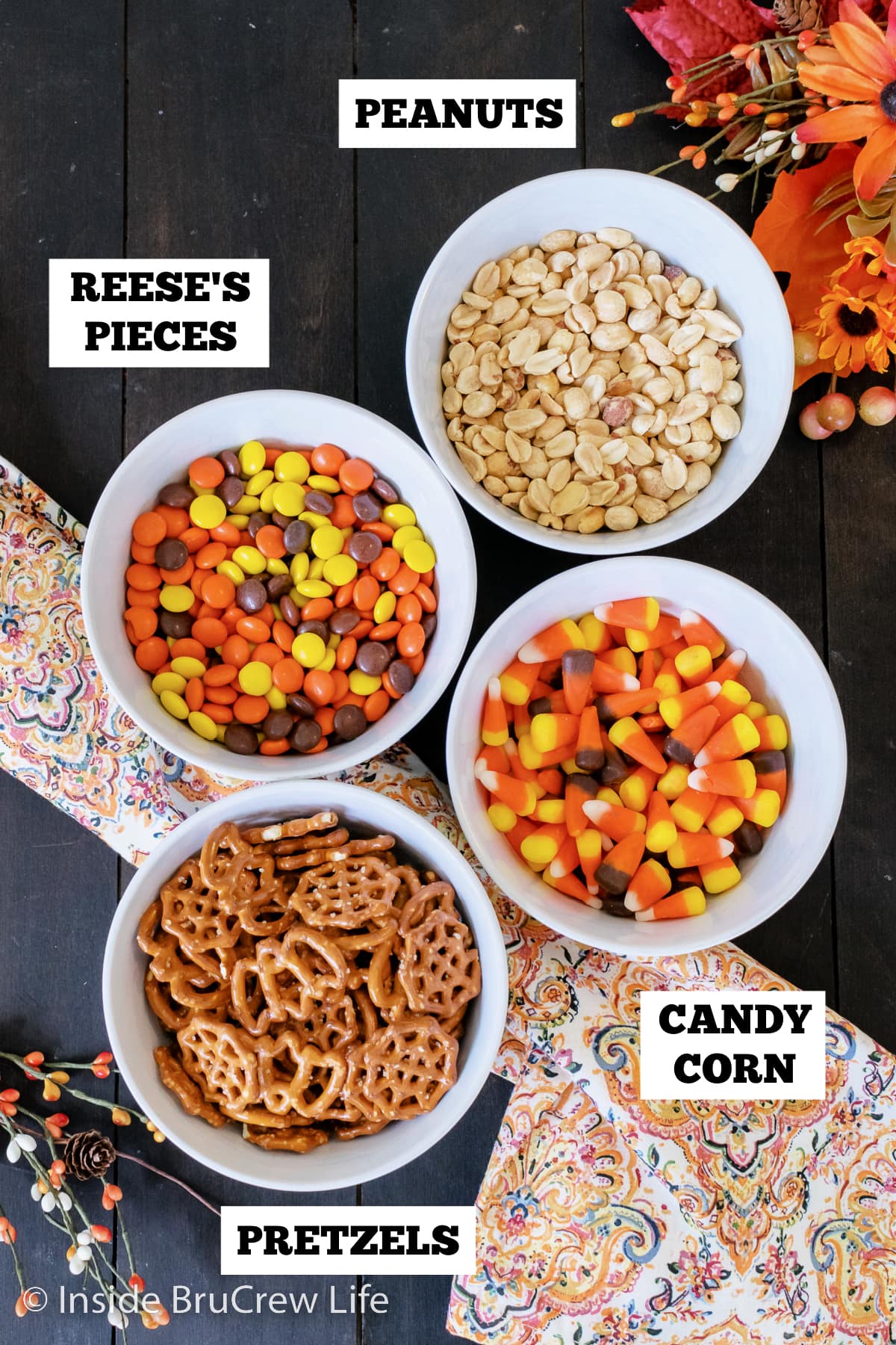 Four bowls filled with ingredients needed for a fall snack mix.