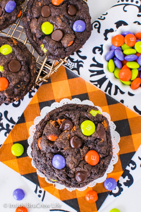 Overhead picture of a stack of Halloween Chocolate Cookies and Cream Cookies on an orange napkin with candies around it